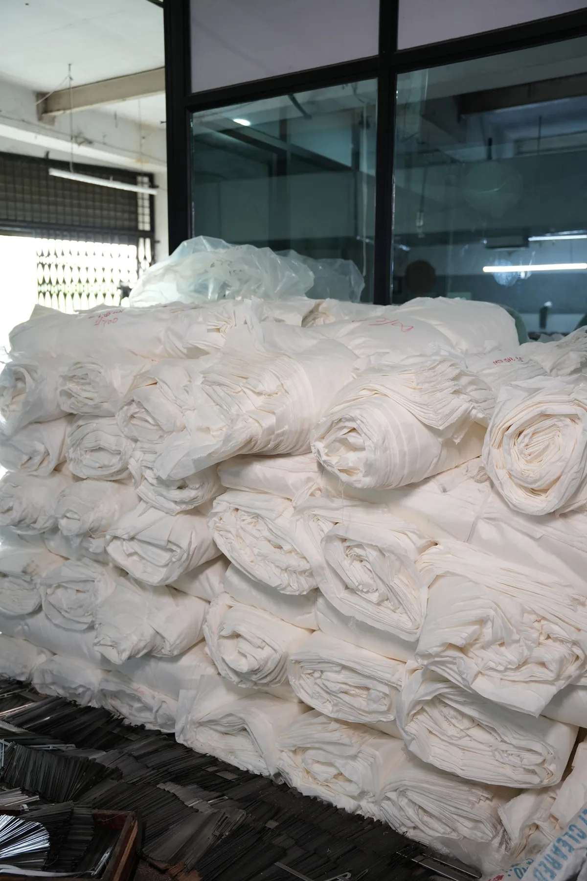 Rolls of woven grey fabric stacked in the godown